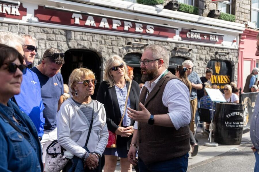 Galway: Food and Culture Walking Tour with Tastings - Medieval city walls and landmark streets, with the guide doing the connecting
